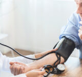 Female nurse checking blood pressure of mature man