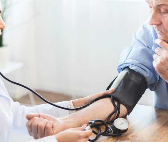 Female nurse checking blood pressure of mature man