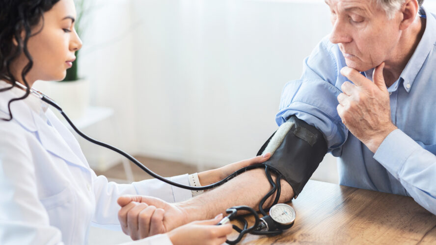 Female nurse checking blood pressure of mature man