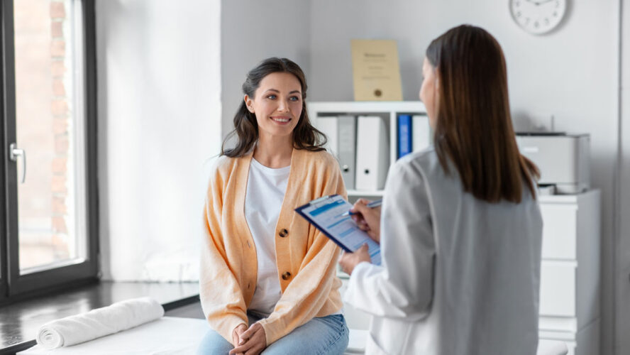 medicine, healthcare and people concept - female doctor with clipboard talking to smiling woman patient at hospital