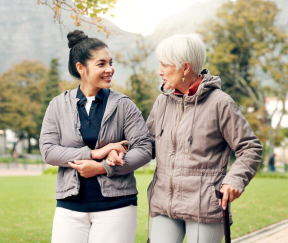 Senior woman, walker and nurse talking in a park with healthcare for elderly exercise. Walking, healthcare professional and female person with peace and physical therapy in a public garden with carer