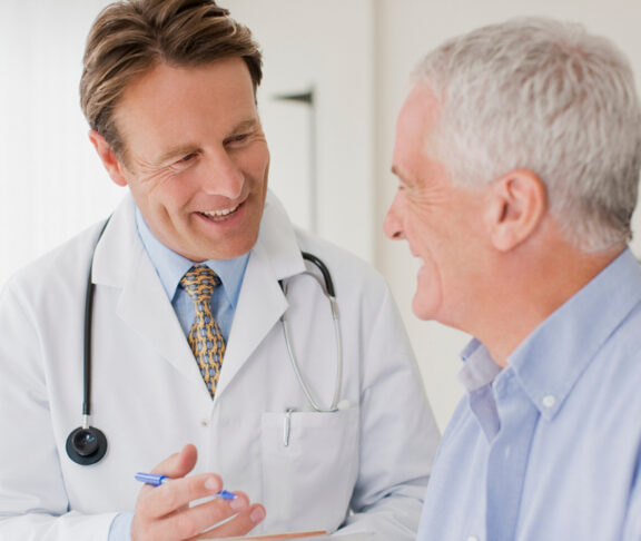 Doctor talking with patient in doctors office - stock photo