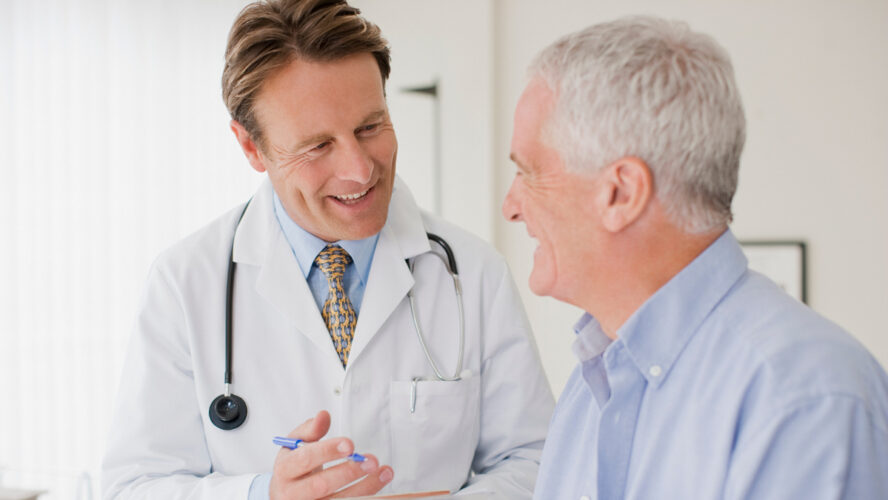 Doctor talking with patient in doctors office - stock photo