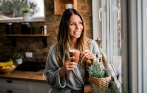 Young woman drinking coffee in the morning, looking at window