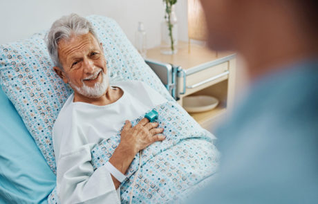 Happy senior patient talking to a nurse while recovering in the hospital ward.