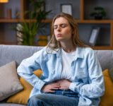 Woman hand in stomach ache, suffer from food poisoning, abdominal pain and colon problem, gastritis. Patient belly, abdomen or inflammation, concept. - stock photo