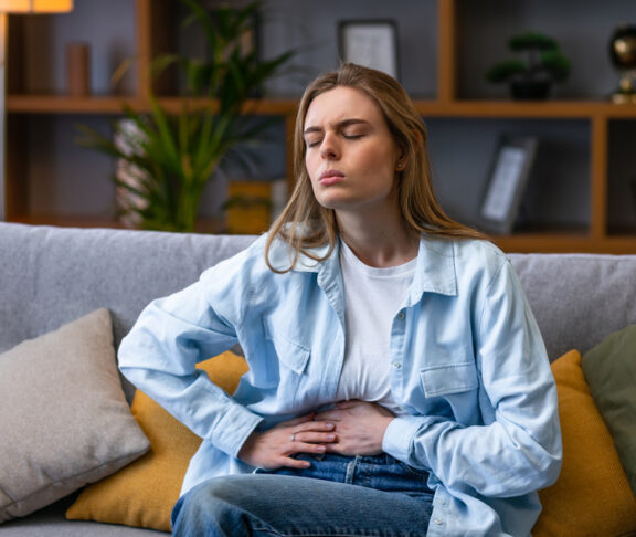 Woman hand in stomach ache, suffer from food poisoning, abdominal pain and colon problem, gastritis. Patient belly, abdomen or inflammation, concept. - stock photo