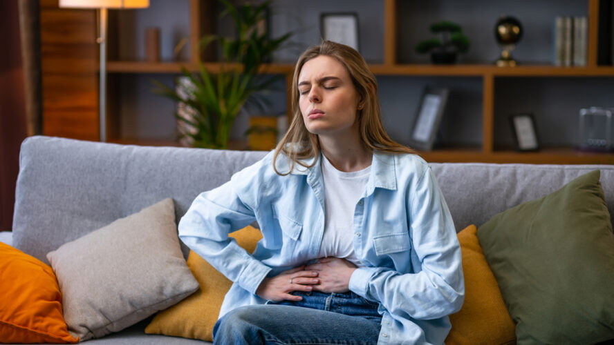 Woman hand in stomach ache, suffer from food poisoning, abdominal pain and colon problem, gastritis. Patient belly, abdomen or inflammation, concept. - stock photo
