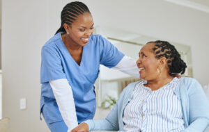 Nurse woman, senior patient and talking for support, healthcare and happiness at retirement home. Black person and happy caregiver together for trust, elderly care and help for health and wellness