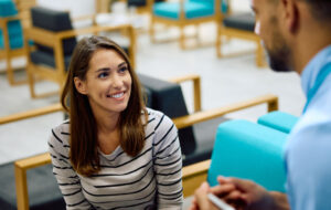 Happy woman talking to medical technician in waiting room at clinic