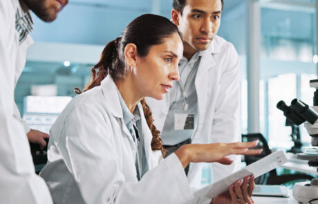 Teamwork, talking or scientists on laptop for medical breakthrough, clinical trial or DNA discovery. People, biology testing or science research in lab with results notes, bacteria or medicine cure