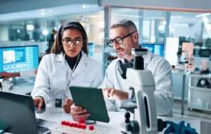 Collaboration, tablet or science with people in lab together for research or development. Innovation, tech and microscope with scientist team in clinical trial for planning or medical investigation