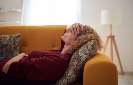 Woman with sinus pain, headache and stomach problems, lying on a couch at home