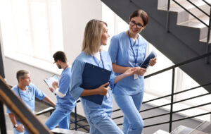 Healthcare workers with tablet and clipboard walking up stairs in hospital
