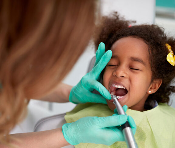 Female dentist patiently polish teeth to child