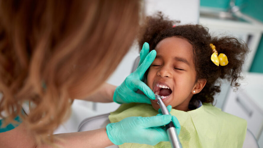 Female dentist patiently polish teeth to child