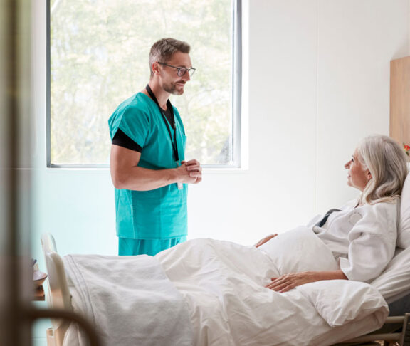 Surgeon Visiting And Talking With Mature Female Patient In Hospital Bed