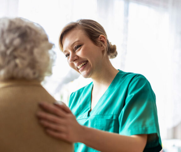 Friendly nurse supporting an elderly lady