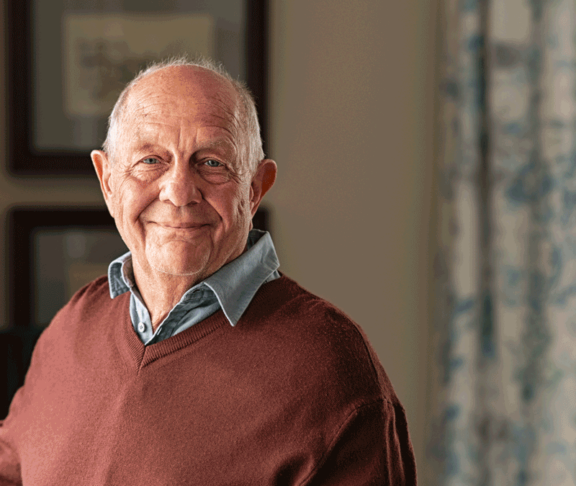 Happy senior man looking at camera at home