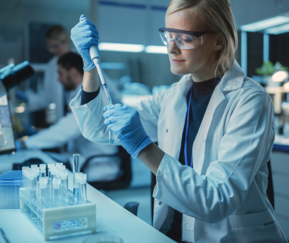 Female Research Scientist Uses Micropipette to Mix Liquids in a Sample Test Tube in a Modern Laboratory.