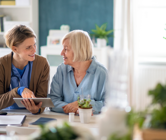 Caregiver or healthcare worker with senior woman patient, using tablet and explaining