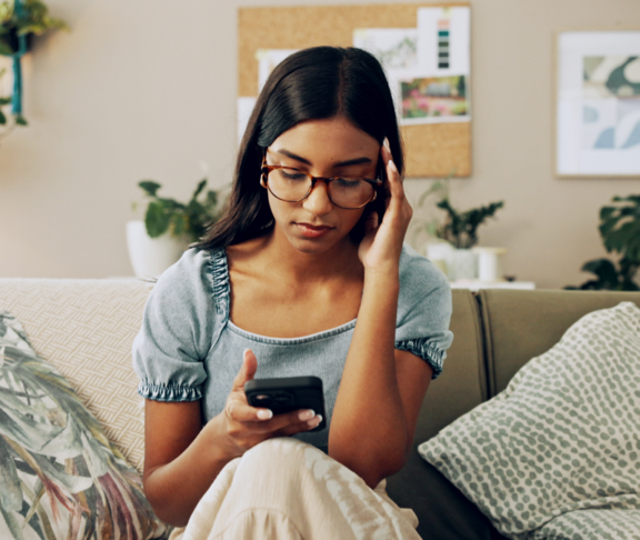 House, stress and woman with smartphone, headache and mistake with communication. Person, apartment and girl on couch, mobile user and cellphone with migraine, online reading and error message