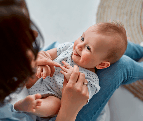 Loving mom carying of her newborn baby at home.Mom and baby boy playing in sunny bedroom. Parent and little kid relaxing at home. Family having fun together. Childcare, maternity concept
